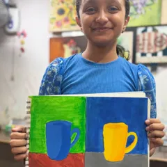 This student's wonderful smile says it all. She is happy with her artwork where she explored different color combinations for the same object study.