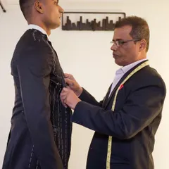 A baste fitting in progress. Relying on a measuring tape alone is not enough. A cloth fitting allows our master tailor to see how the garment sits on the shoulders, neck, and back, making adjustments with large basting stitches.