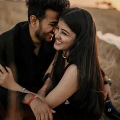 A close up of shared smiles and gentle touches. The warm, golden light of the sunset creates a soft, romantic glow, perfectly highlighting their happy connection.