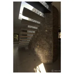 I believe staircases should be sculptural centerpieces. In this apartment for filmmakers, cantilevered concrete steps emerge from a random rubble stone wall, creating a dramatic ascent towards a skylight that bathes the space in natural light.