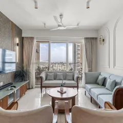 This wide shot of a compact living room at Shapoorji Pallonji Parkwest shows how smart design can maximize space. The light blue sofas and large window create an open, airy feel, while the custom wooden furniture adds warmth and character.