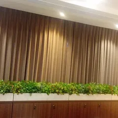 A long planter box filled with lush, low-profile artificial greenery, placed on top of cabinets in an office or boardroom to add a touch of nature.