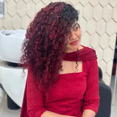 A full view of this stunning red balayage on long, beautiful curls. The color is strategically placed to create dimension and movement, making the curls pop. This shows how vibrant color can work in harmony with natural texture.