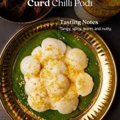 A plate of mini idlis generously coated in my Curd Chilli Podi, highlighting its tasting notes: tangy, spicy, warm, and nutty. It's the perfect way to add a burst of flavour to a simple breakfast.