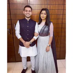 I love creating coordinated looks for couples. Here, we have a custom-made embellished Bundi jacket and raw silk kurta set for him, perfectly complementing her stunning glitter net fish-cut lehenga with an attached dupatta.
