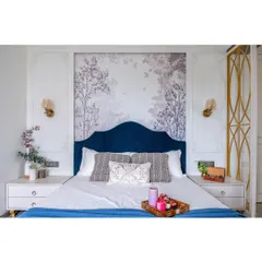 A master bedroom designed as a serene retreat. We balanced a rich blue velvet headboard and a delicate nature-inspired wallpaper with classic wall mouldings and warm lighting to create a space that feels both luxurious and deeply personal.