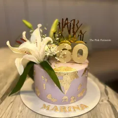 A chic lavender cake for Marina's 60th birthday. The design is elevated with gold leaf details, a "Happy 60" topper, and fresh white lilies.
