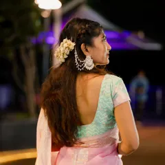 A beautiful back profile shot showcasing an elegant hairstyle with flowers and stunning earrings, paired with a lovely pink saree.