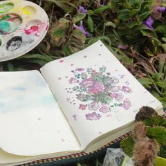 A closer look at my Neelakurinji watercolor painting in my sketchbook, with my paint palette resting on the grass beside it.