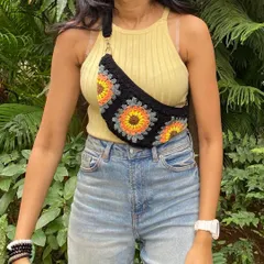Our crochet granny square fanny pack is perfect for when you want to be hands-free. This design features a bright sunflower motif on a black base, combining trendy style with handmade charm. It includes a zip and an adjustable strap for comfort.
