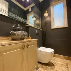 A powder room that makes a statement. This space features a unique stone vessel sink, elegant pendant lighting, and a bold purple ceiling, showing that even small spaces can be packed with personality and luxury.