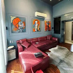 Another view of the TV lounge, showcasing how the natural light from the large window interacts with the space. The strategic placement of the L-shaped sofa creates a cozy corner for relaxation, while the curated artwork provides a strong visual anchor for the room.