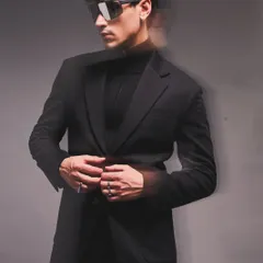 A lesson in monochromatic power. This all black look combines a tailored blazer with a turtleneck and statement sunglasses, creating an edgy, cohesive, and undeniably sharp aesthetic.