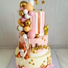 A grand three-tier cake for a first birthday celebration. This design features a cute teddy bear, a cascade of balloons, and sparkling gold stars for a truly festive look.