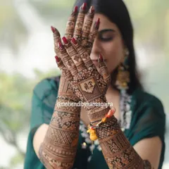 A beautiful pose showing the back of the hands, where a custom monogram is featured prominently. This is a wonderful way to personalize your bridal mehendi.