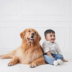 A heartwarming portrait of a baby boy and his golden retriever sitting side-by-side, showcasing the special bond between a child and the family pet.