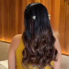 A detailed back view of a baby shower hairstyle, with soft waves, delicate braids, and a traditional latkan accessory for a festive touch.