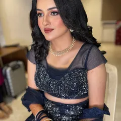 An elegant and modern reception look featuring a navy blue lehenga. The makeup is soft and glamorous with a neutral lip, paired with crimped waves for a chic hairstyle.