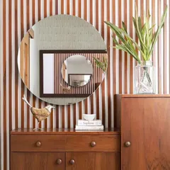 This wall features vertical wood battens, creating a fluted effect that adds texture and visual interest. The round mirror provides a soft contrast to the linear pattern.
