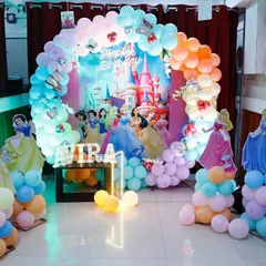 A magical Disney Princess theme for a first birthday. This enchanting setup features a pastel rainbow balloon arch, a castle backdrop, and life-sized cutouts of Cinderella, Snow White, and other princesses, creating a fairytale experience.