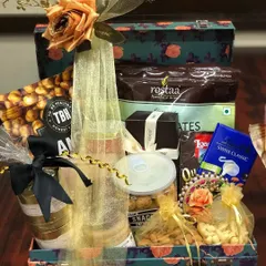 A luxurious welcome hamper packed in a floral-printed trunk box. This gift is filled with premium snacks, dry fruits, and chocolates, perfect for making guests feel pampered.