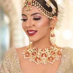 A beautiful bride looking radiant in a custom red and orange meenakari choker set. The matching mathapatti and nath complete her elegant and traditional look.