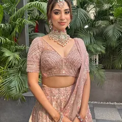 This bride looks like she's straight out of a Pinterest board. Her pastel pink lehenga is styled with soft makeup and a chic, pearl-adorned bun for a dreamy look.