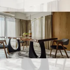 A full view of the live-edge dining table with its unique circular metal bases. The set is paired with custom-made dining chairs that have upholstered seats and curved wooden backrests, creating a modern and organic dining space.