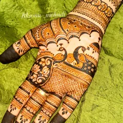 A close-up of the palm, highlighting two graceful peacocks amidst a backdrop of fine lattice work. The design is framed by lotus flowers and intricate borders, showing a mastery of detail.