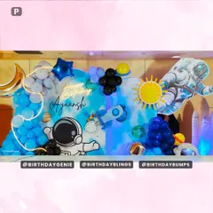 A wide view of the elaborate space-themed setup, featuring a watercolor-style galaxy backdrop, multiple astronaut cutouts, and a neon "Happy Birthday" sign.