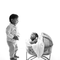 A classic black and white version of a big brother meeting his new baby sister. This timeless style really emphasizes the emotion of the moment.