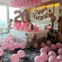 A pretty-in-pink 20th birthday celebration. This hotel room is filled with pink balloons on the ceiling and floor, complemented by rose gold number and letter foils for a fun and youthful vibe.