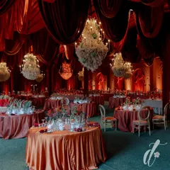 We transformed this space into a dramatic and opulent reception hall using a rich, red color palette and luxurious velvet draping. The scene is set with dozens of floral chandeliers, creating a warm, intimate, and truly grand atmosphere for an evening celebration.