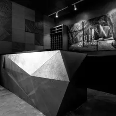 A monochrome view of the cubism-inspired bar, designed and executed in radiant brass. This image highlights the bar's sharp, angular form and its role as a sophisticated, sculptural centerpiece in the restaurant.