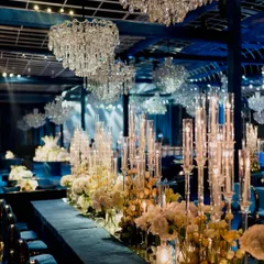 A detailed look at the tablescape from our blue-themed gala. A mirrored tabletop reflects the endless crystal chandeliers and towering candelabras, while a dense runner of white carnations and roses adds a layer of soft, classic beauty.