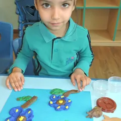 A student carefully crafts flowers from clay during our 'Clayazy' competition, focusing on details and bringing her artistic vision to life.