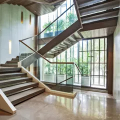 The main staircase is the heart of the home. We positioned it strategically to invite natural light through a screened glass facade, balancing openness with privacy and creating a powerful dynamic that connects the inside to the greenery outside.