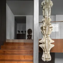 A delicate kirigami installation, crafted from parchment leather in collaboration with Ankon Mitra, sits near a staircase. Its quiet, textural quality adds a layer of tactility and artistry to a transitional space.