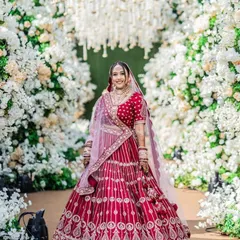 A full-length shot of the bride against a beautiful floral arch. Her classic red lehenga and my signature flawless makeup come together to create a truly breathtaking bridal moment.