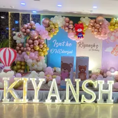 An angled view of the teddy bear themed stage, highlighting the hot air balloon prop and the extensive balloon garland.