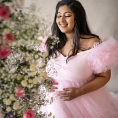 The pure joy of feeling your baby move. This candid shot captures a beautiful, genuine smile, surrounded by the soft colors of the floral arrangement.