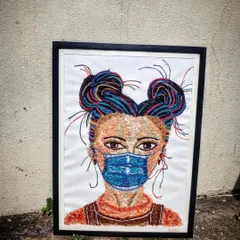 The completed and framed thread art piece, ready to be hung. The black frame provides a strong contrast to the colourful artwork.