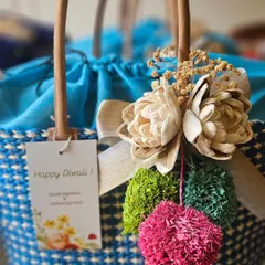 This blue and white patterned raffia basket was created for a client's Diwali gifting. It includes a personalized "Happy Diwali" tag and is adorned with bright, festive pom-poms, showing how we customize even our eco-friendly options.