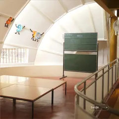 The interior of the kindergarten building, with its high, curved ceiling and low windows at a child's eye level. The space feels vast and playful, like a giant toy.
