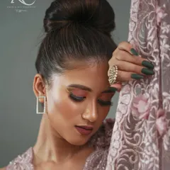 This close-up portrait focuses on the mood of the collection. It highlights the makeup, the elegant updo, and the texture of the embroidered fabric, creating an image that is both a beauty shot and a detailed garment feature.