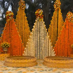 For this haldi ceremony at a farmhouse, I created a unique backdrop with triangular panels made entirely of fresh marigold and tuberose strings. The two golden urlis in the front are ready for the ceremony's rituals.