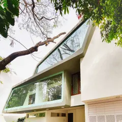 This view highlights how the unique, angled glass facade of the 'Mobius' house was designed to frame the branches of an existing tree. Our landscape plan was built around preserving such natural features, making them integral to the home's identity.