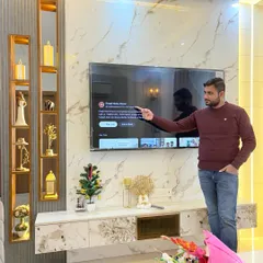 Pointing out the details of our custom TV unit. The combination of materials, including marble-finish laminate, wood, and gold accents, creates a rich and luxurious feel.