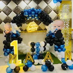 A fun Boss Baby theme for a first birthday, complete with character cutouts, a themed balloon arch, and a large marquee number '1'.