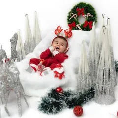 A tiny reindeer in a winter wonderland. For this Christmas mini session, we created a clean, white backdrop with festive silver and red decorations to make this baby's first holiday portrait truly special.
